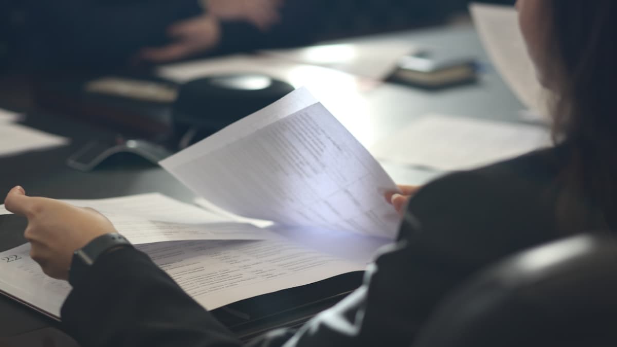 Gros plan sur des mains qui parcourent les pages d'un rapport imprimé.
