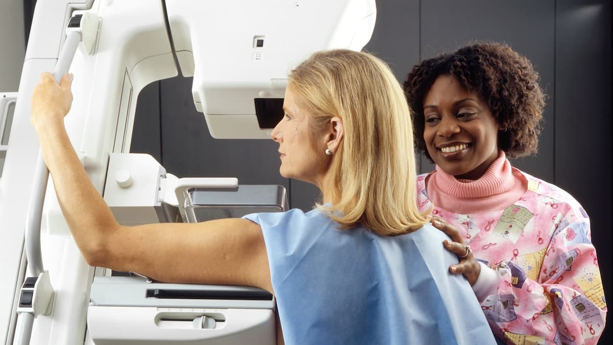 Une professionnelle de santé accompagne une patiente pendant un examen de dépistage, dans le calme.