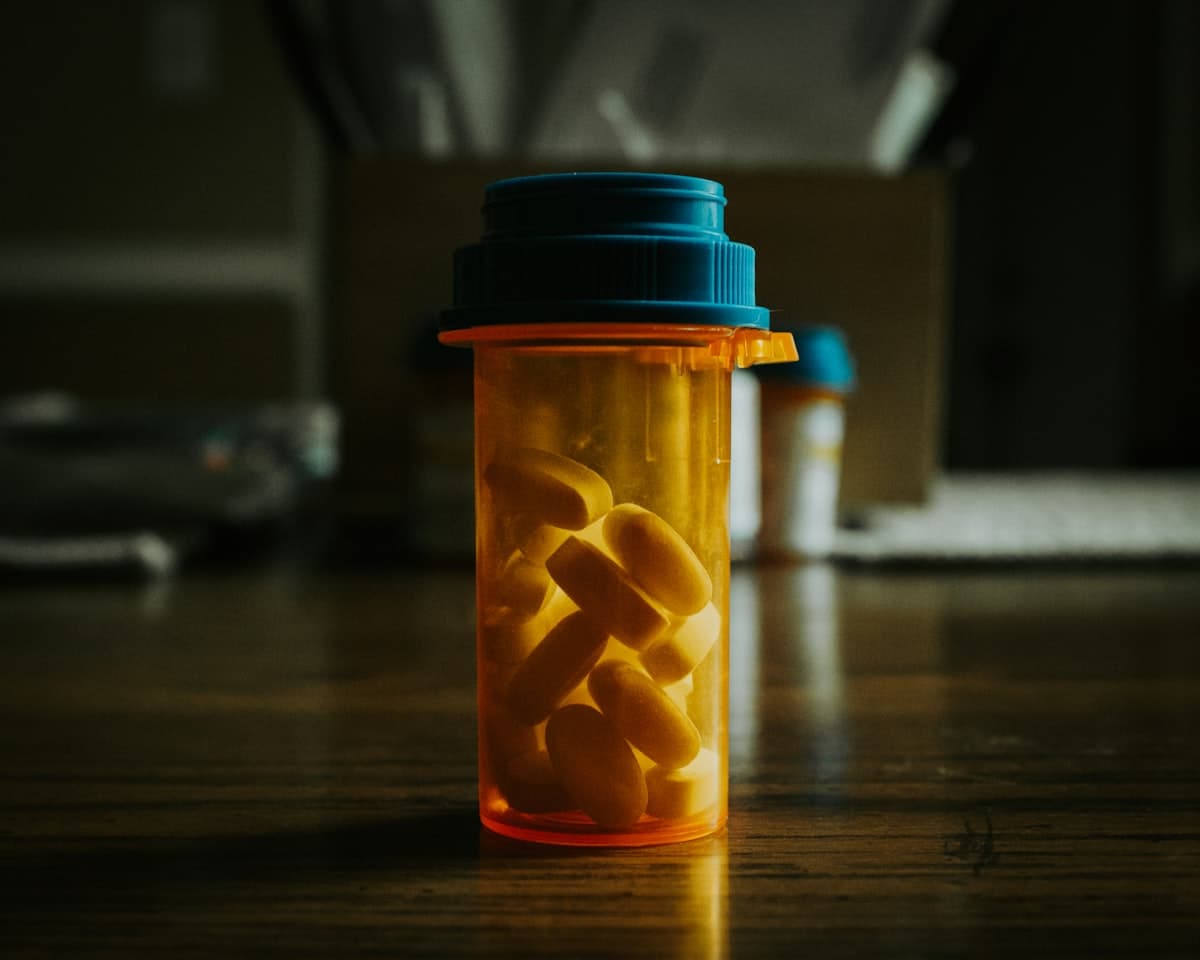 Flacon de médicaments rempli de comprimés posé sur une table en bois