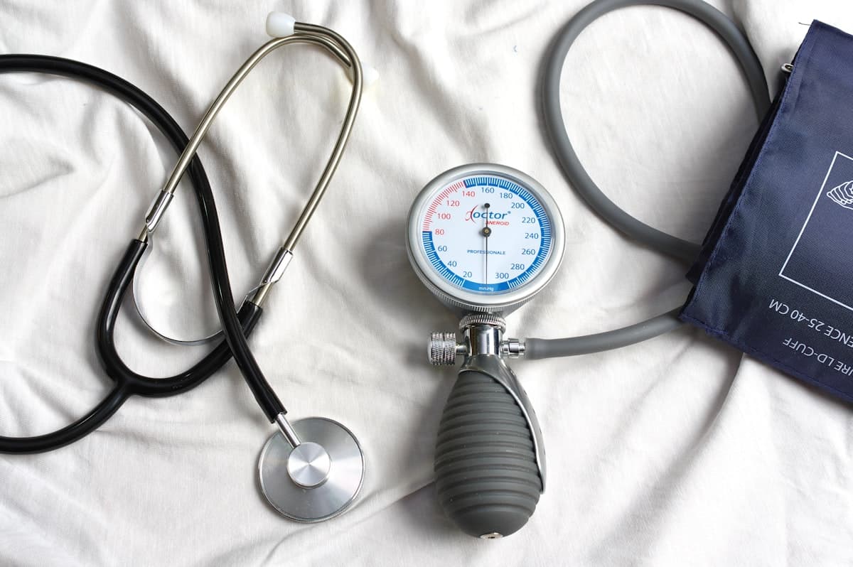 Un tensiomètre et un stéthoscope posés sur un lit, prêts pour une visite infirmière à domicile.